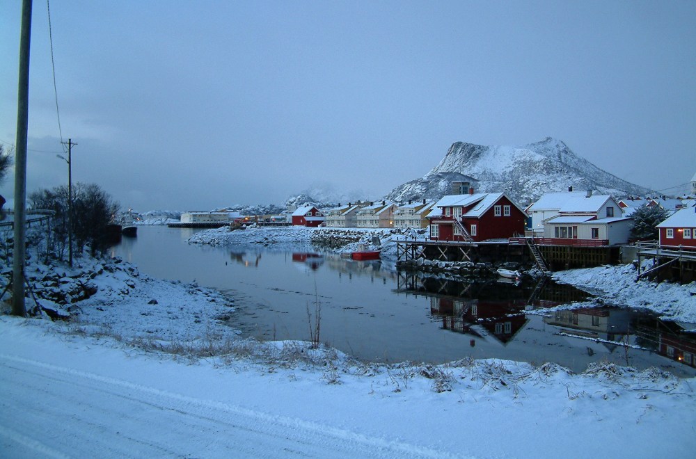 Colorful fishing houses line the fjord in the snow-covered town of Svolvær in Lofoten